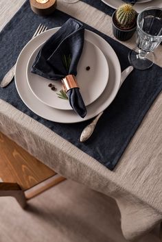 a place setting with silverware and black napkins