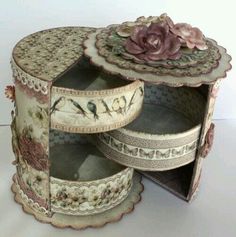 an open box with flowers on the lid and decorative paper around it, sitting on a white surface