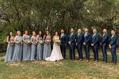 a group of people standing next to each other in front of some trees and grass