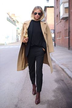 a woman walking down the street wearing a trench coat