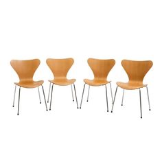 four chairs with metal legs and wooden seats on each side, one in the shape of an egg