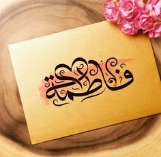 a piece of paper with an arabic writing on it next to pink flowers and leaves