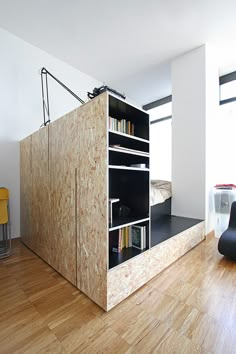 a room with a book shelf, chair and bed in it that is made out of plywood