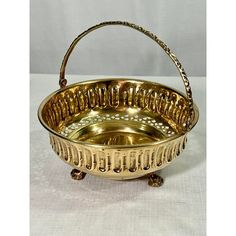 an antique brass basket with handles and beaded trimmings, on a white background