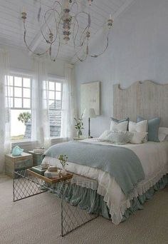 a bed room with a neatly made bed and a chandelier hanging from the ceiling