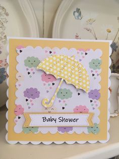 a baby shower card with an umbrella on the front, and flowers in the background