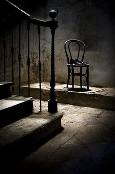 an empty chair sitting on the steps in a dark room