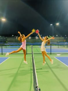 two women playing tennis in the rain at night