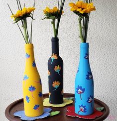 three vases with flowers in them sitting on a wooden table next to each other