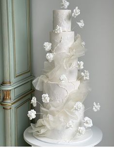 a three tiered white wedding cake with flowers on top