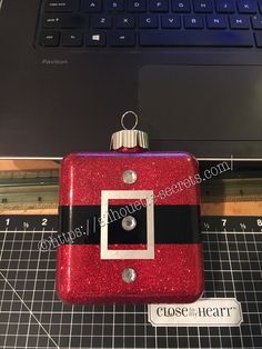 a close up of a red and black christmas ornament near a laptop computer