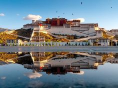 the potala palace sits on top of a hill with its reflection in the water