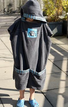 a young child wearing blue slippers and a gray hooded jacket standing on the sidewalk