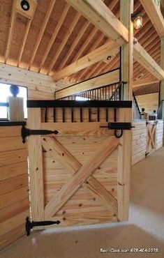 an open barn door in the middle of a room with wooden walls and beams on the ceiling