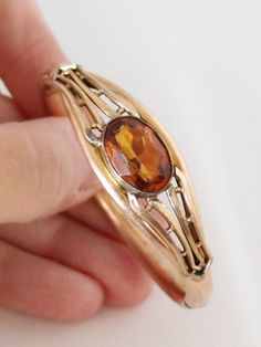 "Please note we ship on Tuesdays and Fridays only due to living in a Rural community. (THIS ITEM IS NOT GOLD PLATED IT IS ANTIQUE OR VINTAGE GOLD FILLED PLEASE READ EPLANATION FOR VINTAGE AND ANTIQUE GOLD FILLED JEWELLERY BELOW THE DESCRIPTION) This is an Edwardian Rose Gold Filled Topaz Glass Stone Bangle early 1900s and for a petite wrist only. Inside circumference is 14.5cms or approximate 5.75 inches. Good Antique condition. No dings or dents. Push button to open and snap shut. Hinge can gape occasionally but secures back in Stone is paste and is multi faceted and bezel set with open back to let the light shine through. Weighs 13.7gms. Band is 6-7mm wide. Stone is 1.6cms wide. Suitable for petite woman or discerning teenager. Signed on  the inside band A C Co (Attleboro Chain Company U Antique Oval Bangle For Formal Occasions, Collectible Gemstone Bangle Bracelets, Oval Gemstone Bangle For Formal Events, Victorian Polished Bracelets For Formal Occasions, Classic Gemstone Bangle Jewelry, Vintage Gold Bracelet With Polished Finish For Formal Occasions, Heirloom Gemstone Bracelet Jewelry, Antique Rose Gold Bracelets For Formal Occasions, Heirloom Gemstone Bracelet