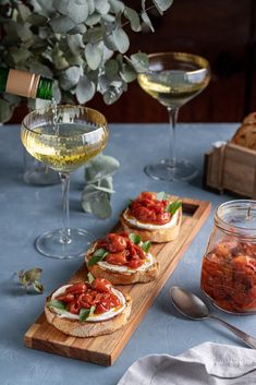 there are three sandwiches on the table with wine and bread in front of them, along with two glasses of wine