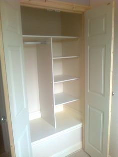 an empty closet with white shelves and doors