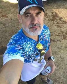 a man in a blue and white shirt is holding a tennis racket while wearing a hat