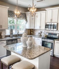 a kitchen with white cabinets and granite counter tops, two stools at the island