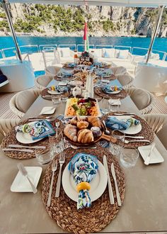 the table is set with plates, silverware and croissants on it