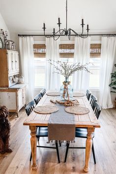 a dining room table with place settings on it, and a dog in the background