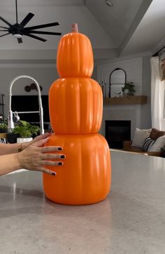 an orange pumpkin sitting on top of a counter next to a woman's hand