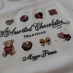 an embroidered t - shirt with chocolates and other items on the front that says, assorted chocolates tradition