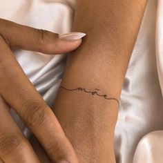 a woman's hand with a small tattoo on her left wrist and the word love written in cursive writing