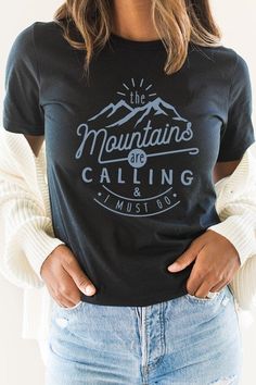 Introducing our "The Mountains Calling And I Must Go" Graphic Tee, a perfect choice for adventure enthusiasts and outdoor lovers. Most t shirt colors are 52/48 cotton/poly blend. White and Cream tees are 100% cotton, Ash tees are 99/1 cotton/poly. Available in various sizes, it's an excellent addition to outdoor retail stores and adventure-themed boutiques. Encourage your customers to answer the call of the mountains with our "The Mountains Calling And I Must Go" Graphic Tee. By Kissed Apparel.M Black T-shirt With Letter Print For Outdoor, Blue T-shirt With Letter Print For Outdoor, Black Letter Print Top For Outdoor, Black Letter Print T-shirt For Outdoor, Crew Neck T-shirt With Letter Print For Hiking, Blue Graphic Tee For Outdoor Activities, Blue Tops With Screen Print For Outdoor Activities, Black Letter Print T-shirt For Hiking, Casual Slogan T-shirt For Outdoor