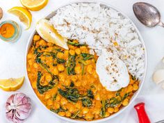 a bowl filled with rice, chickpeas and spinach next to lemon wedges