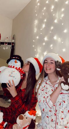 two girls in pajamas and hats holding stuffed animals