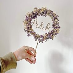 a person holding a flower wreath with the word love spelled in it