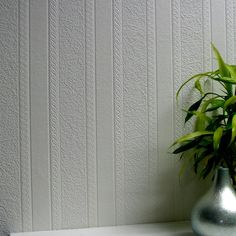 a potted plant sitting on top of a white shelf in front of a wall