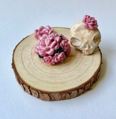 two small pink flowers sitting on top of a piece of wood next to each other