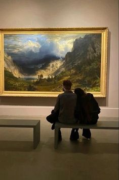 a person sitting on a bench in front of a painting with mountains and clouds behind them