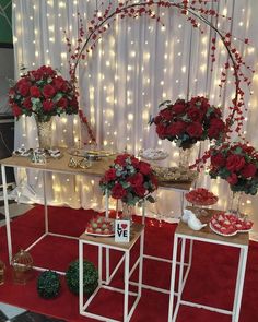 a table with red flowers and desserts on it