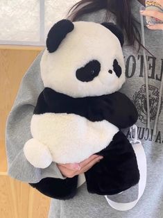 a woman holding a stuffed panda bear in her arms