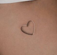 a small heart tattoo on the back of a woman's stomach is shown in black and white