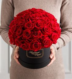 a woman holding a black box with red roses in it's hands and the lid is open