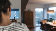 a man is using an app on the wall in his living room and dining room