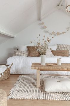 a room with white walls and wooden flooring is furnished with natural materials such as wicker furniture