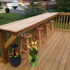 a wooden deck with stools and flowers on it