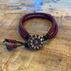 a wooden table topped with two bracelets and a flower on top of each other