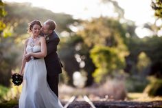 a bride and groom embracing each other in front of trees