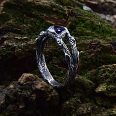 a silver ring sitting on top of moss covered rocks