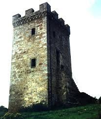 an old stone tower sitting on top of a lush green hillside