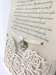 a wedding card with a white rose on it and a heart charm attached to the front