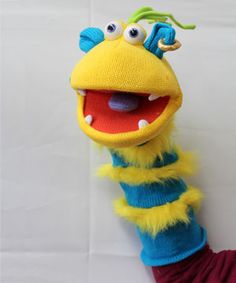 the puppet is wearing a blue and yellow striped shirt with green hair, while it's holding on to a red arm