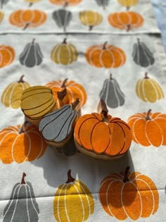 three wooden pumpkins are sitting on a tablecloth with orange and yellow designs around them