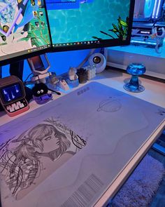 a computer desk with two monitors and drawings on it